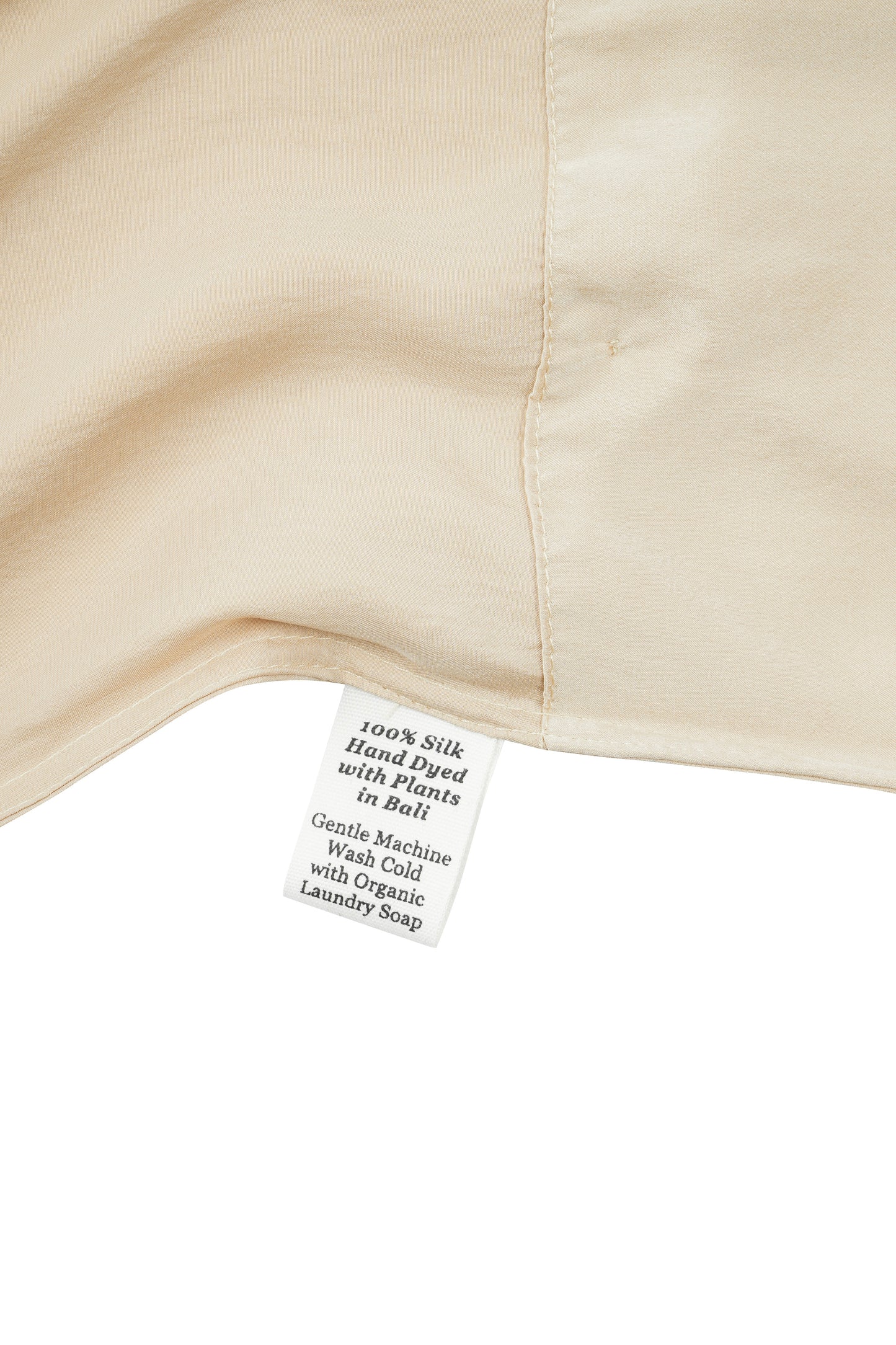 Close-up of a silk in vanilla with a label detailing care instructions