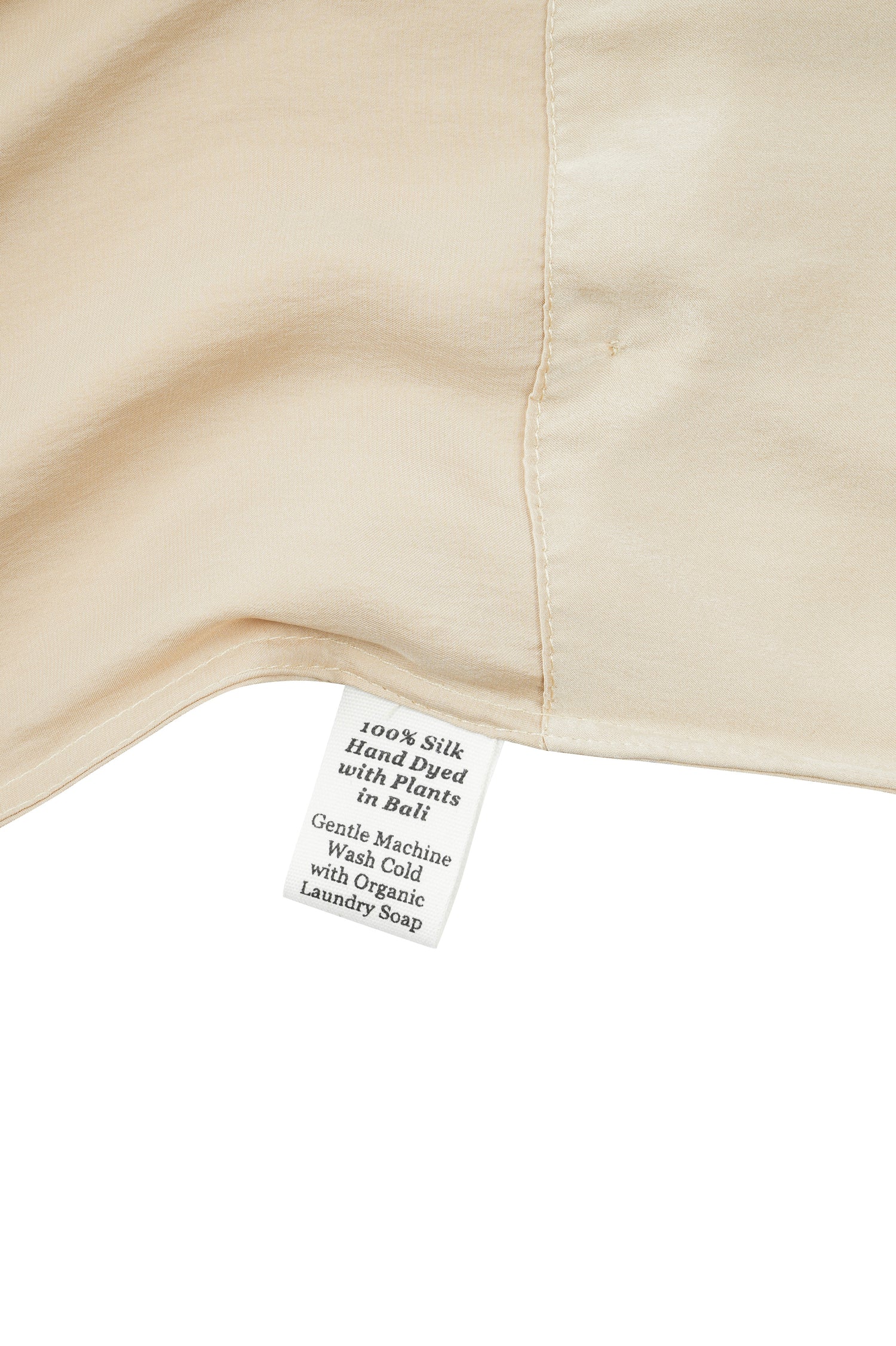 Close-up of a silk in vanilla with a label detailing care instructions